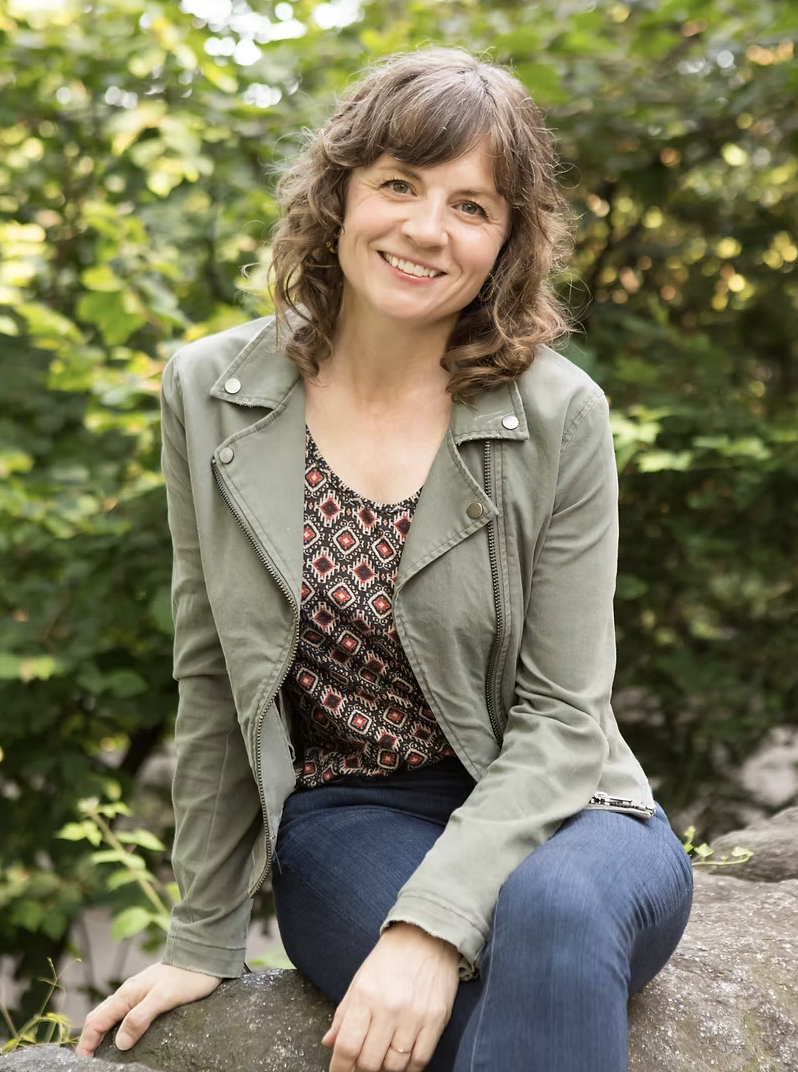 Sarah smiling, seated outdoors